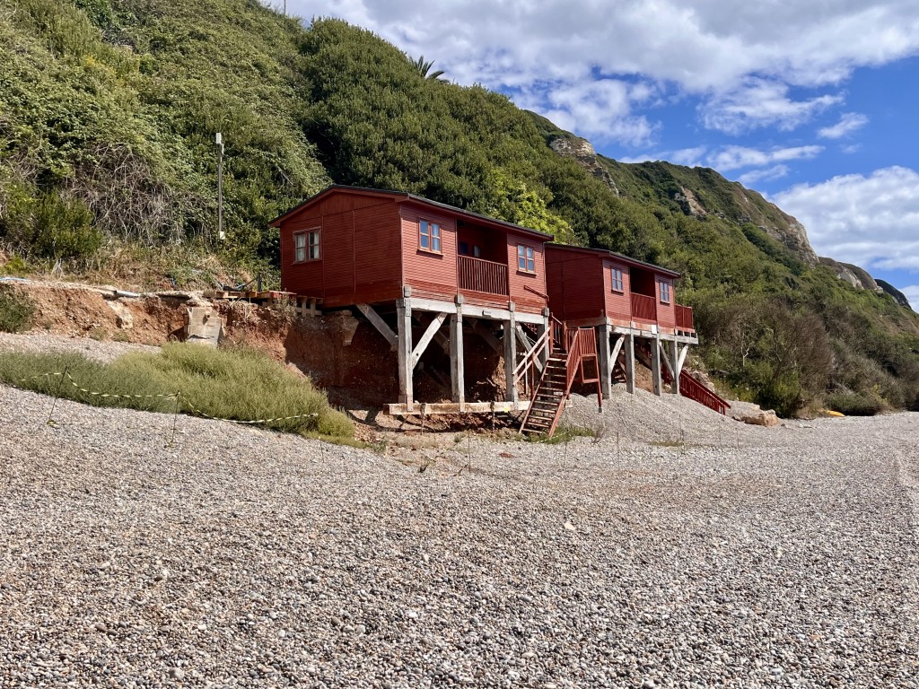 Lot: 110 - STRUCTURALLY DAMAGED BEACH HUT IN BEACH LOCATION, FOR REPAIR - general view of chalets